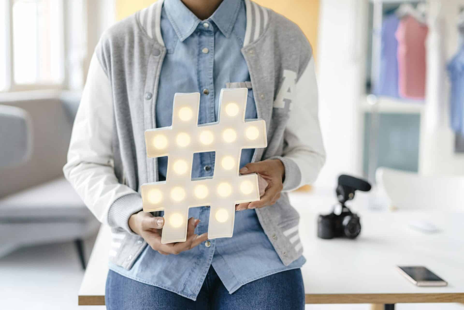 Young woman holding hashtag sign in studio